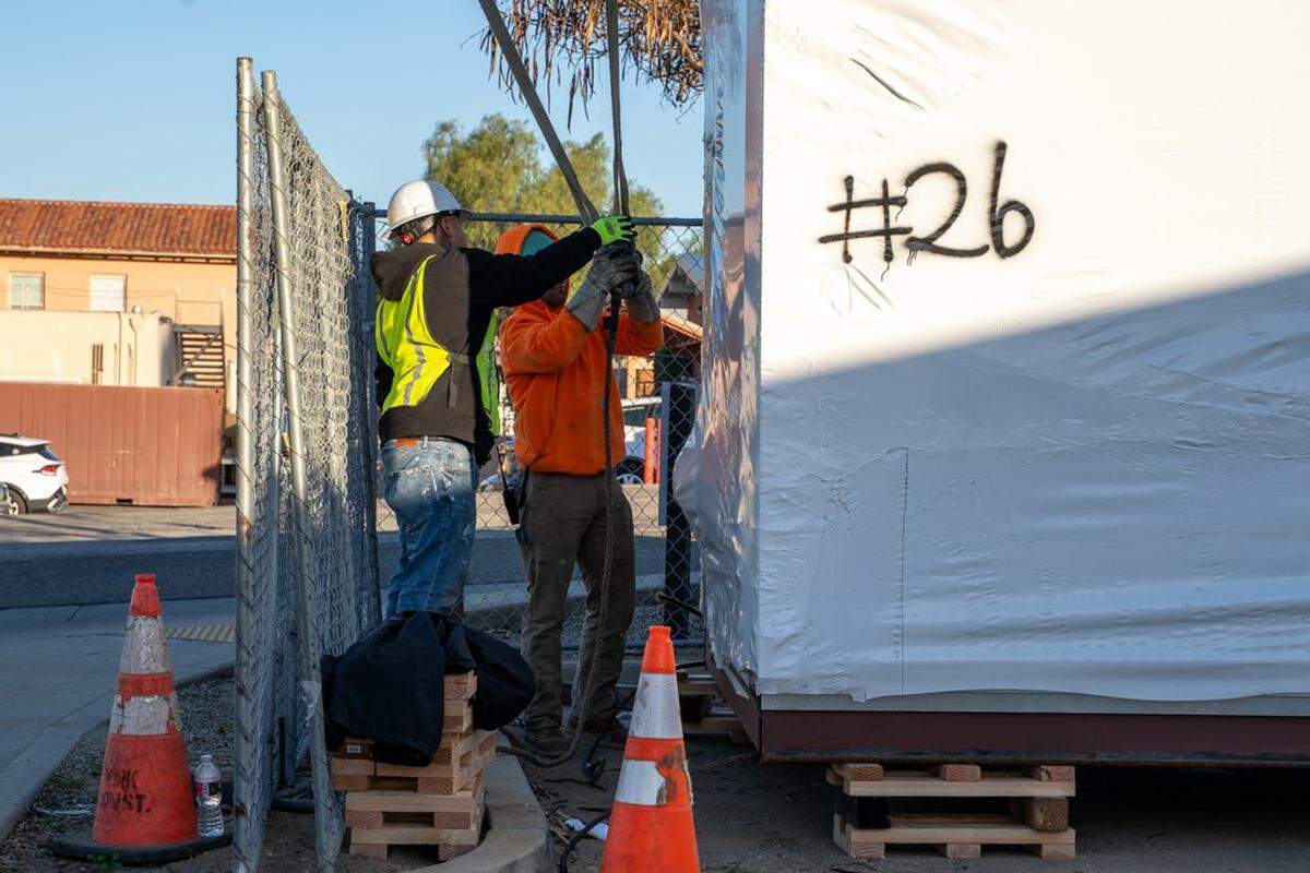 A construction crew attaches a crane hoist to a prefabricated home at the Welcome Home Village project site on Thursday, Feb. 5, 2026. The Welcome Home Village will consist of 54 prefabricated, 3D-printed homes that will house homeless individuals.