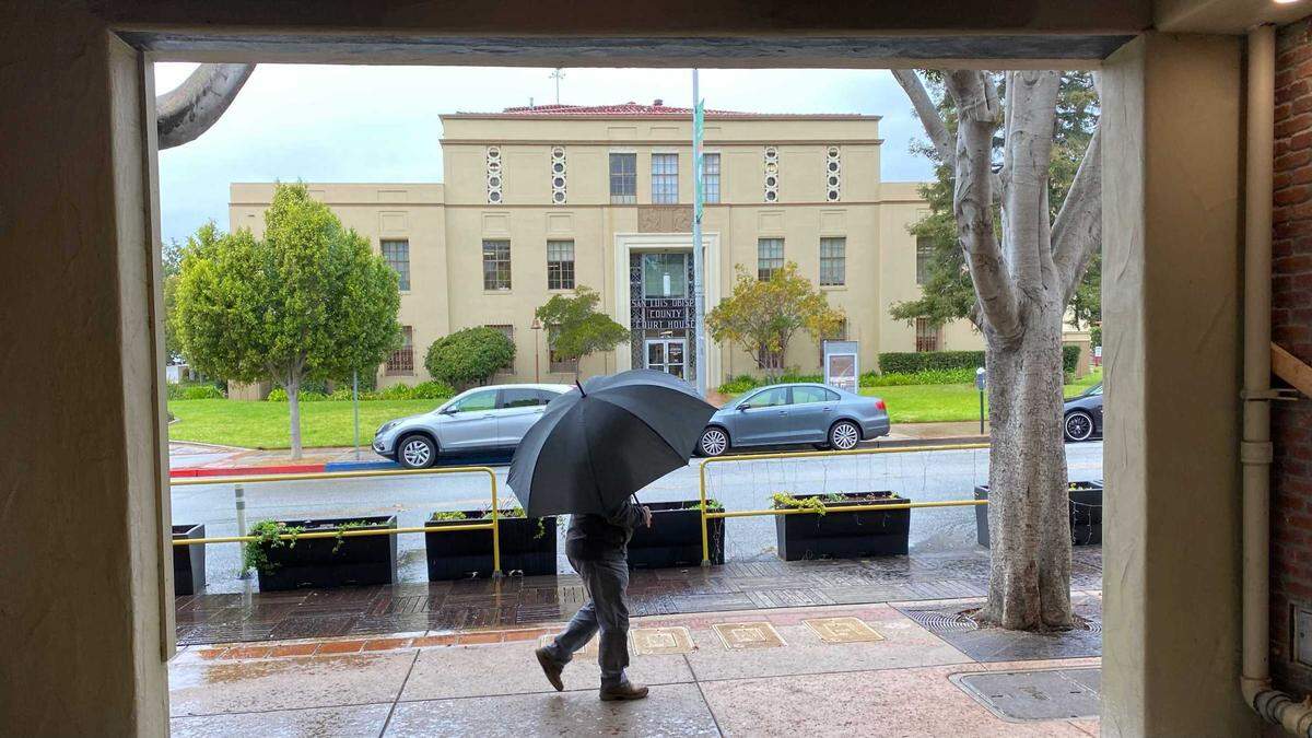 A man takes shelter under an umbrella during a recent rain storm.