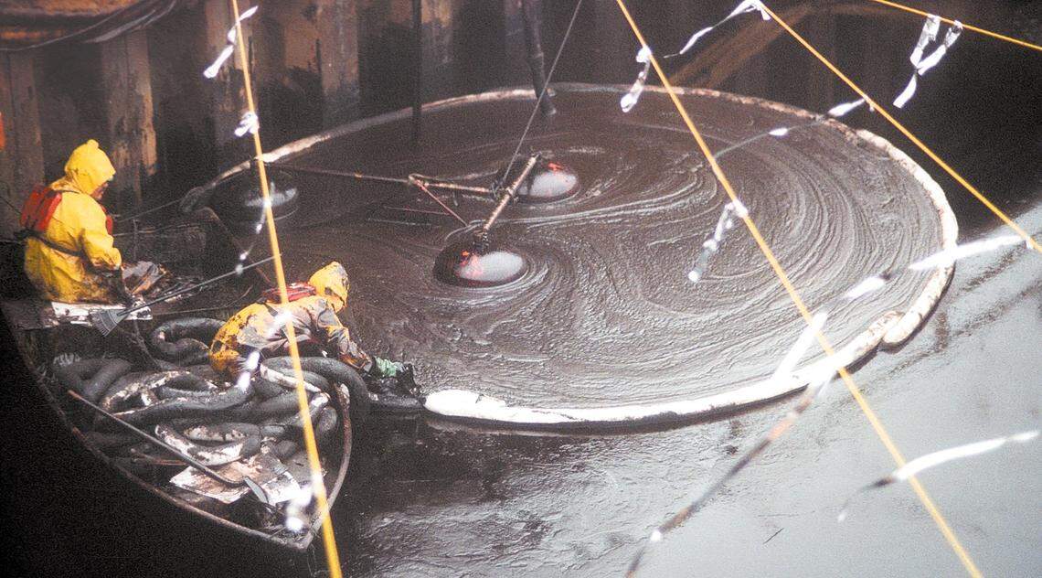 Contractors skim oil from a pool excavated in Avila Beach near San Luis Creek in this file photo from December 13, 1995. The yellow rope with reflective ribbon was to keep bird from landing in the goo. Much of Front Street was demolished for a Unocal funded clean up due to leaking oil pipes.