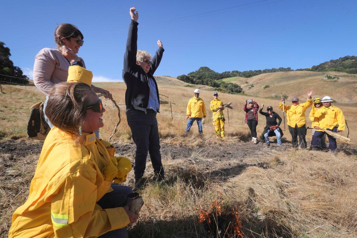 Tribal Chair, Mona Olivas Tucker lead the first ignition and celebrates with upraised arms. The yak titʸu titʸu yak tiłhini Northern Chumash Tribe celebrated lighting the first cultural burn in San Luis Obispo County. They lead a 15-acre cultural burn at the Johnson Ranch Open Space on Tuesday, June 18, 2024.
