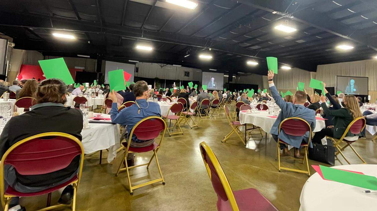 Attendees at the 2021 Central Coast Economic Forecast hold green or red signs in the air to indicate whether their businesses have struggled with finding workers in the past year.