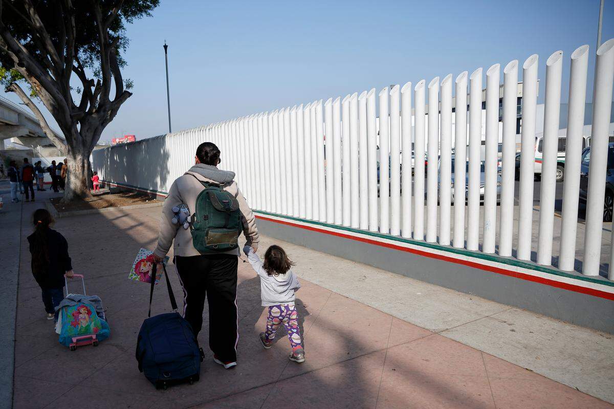 In this April 25, 2019 image, a woman from the Mexican state of Michoacán leads her two daughters in Tijuana, Mexico, after their names were called from a list to apply for asylum in the United States.