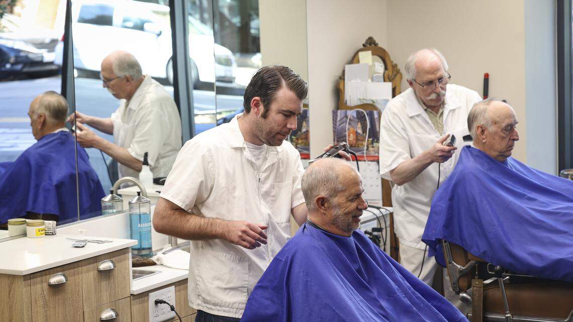 Barbers Ben Fleming, left and Ray Shearer give haircuts to Tom Dorich, left, and Michael Kennedy. The Anderson Barber Shop has moved back to its original location on Monterey Street, seen here on April 7, 2026.