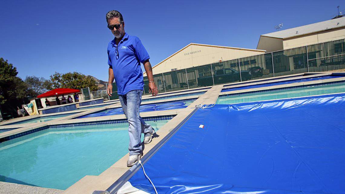 Lee Valenzuela, a board member with the National Plasterers Council, walks past one of several pools at Cal Poly that are being used in a study to determine the effectiveness of pool covers in reducing evaporation.