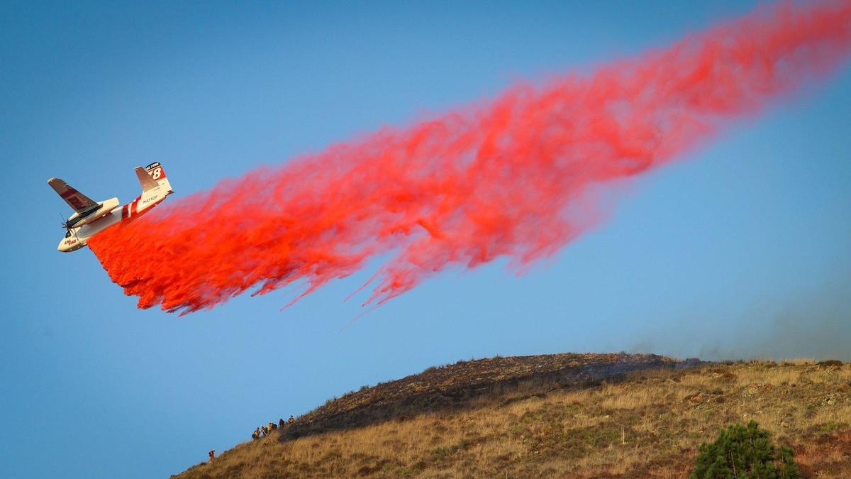 Air tanker makes a drop near firefighters above San Luis High School. Firefighters battled a quick-moving fire in the hills above San Luis High School on Oct. 30, 2023.