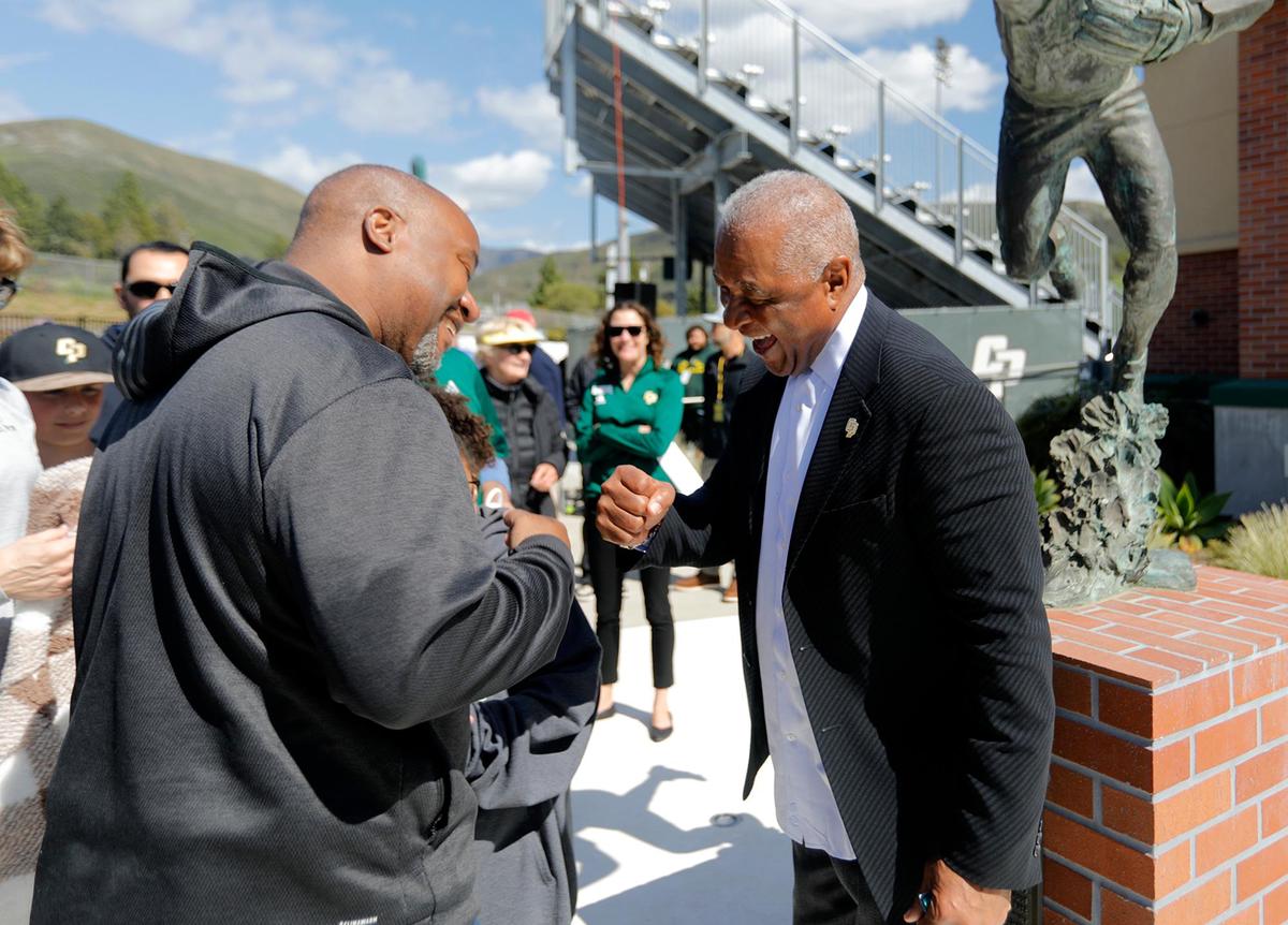 Jamie Patton of San Luis Obispo gets a fist-bump from Ozzie Smith. The baseball legend returned to Cal Poly for the re-dedication of his statue and plaza at Baggett Stadium in San Luis Obispo on March 25, 2023.