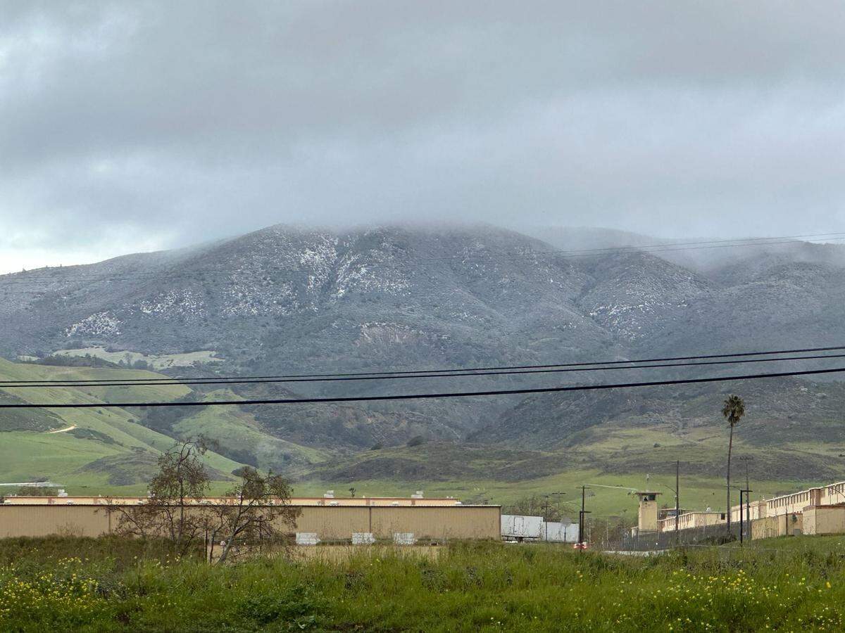 Snow is seen in the hills behind California Men’s Colony state prison off Highway 1 north of San Luis Obispo on Thursday, Feb. 23, 2023.