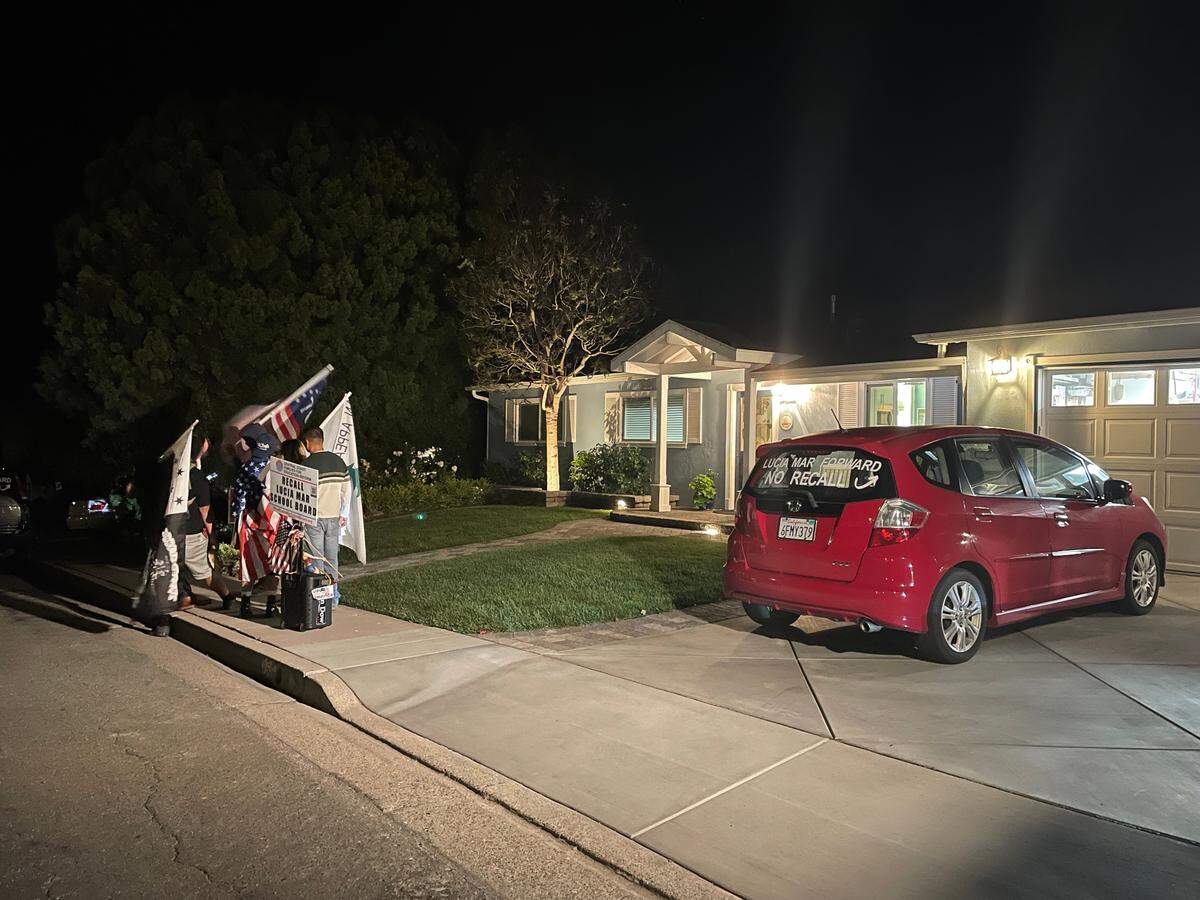 People surround a speaker to listen to the Lucia Mar Unified School District Board of Trustees meeting Tuesday evening. The people were loudly protesting the virtual meeting outside of board member Colleen Martin’s home in Arroyo Grande.