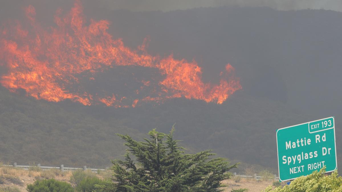 Wind-whipped flames burn on the hillside next to Highway 101, above Shell Beach.