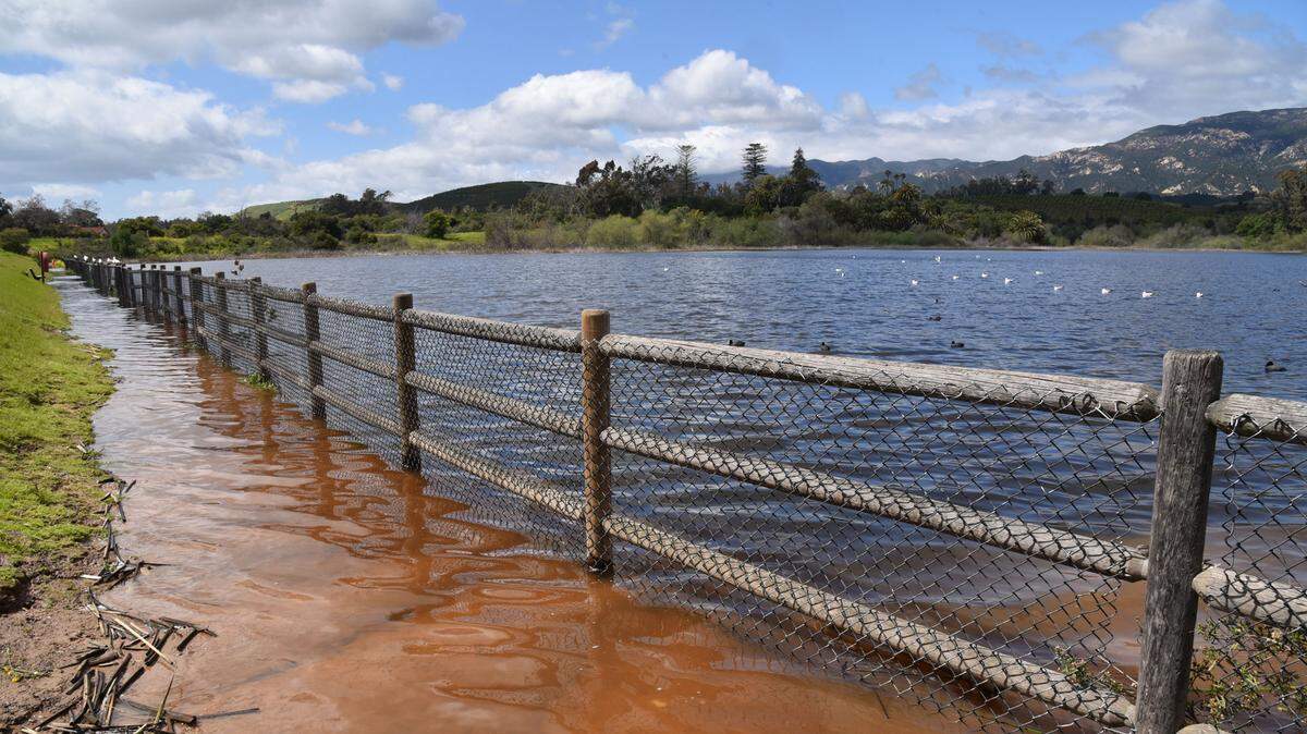 Water from a full Lake Los Carneros in Goleta spills over the lower walkway along the dam.