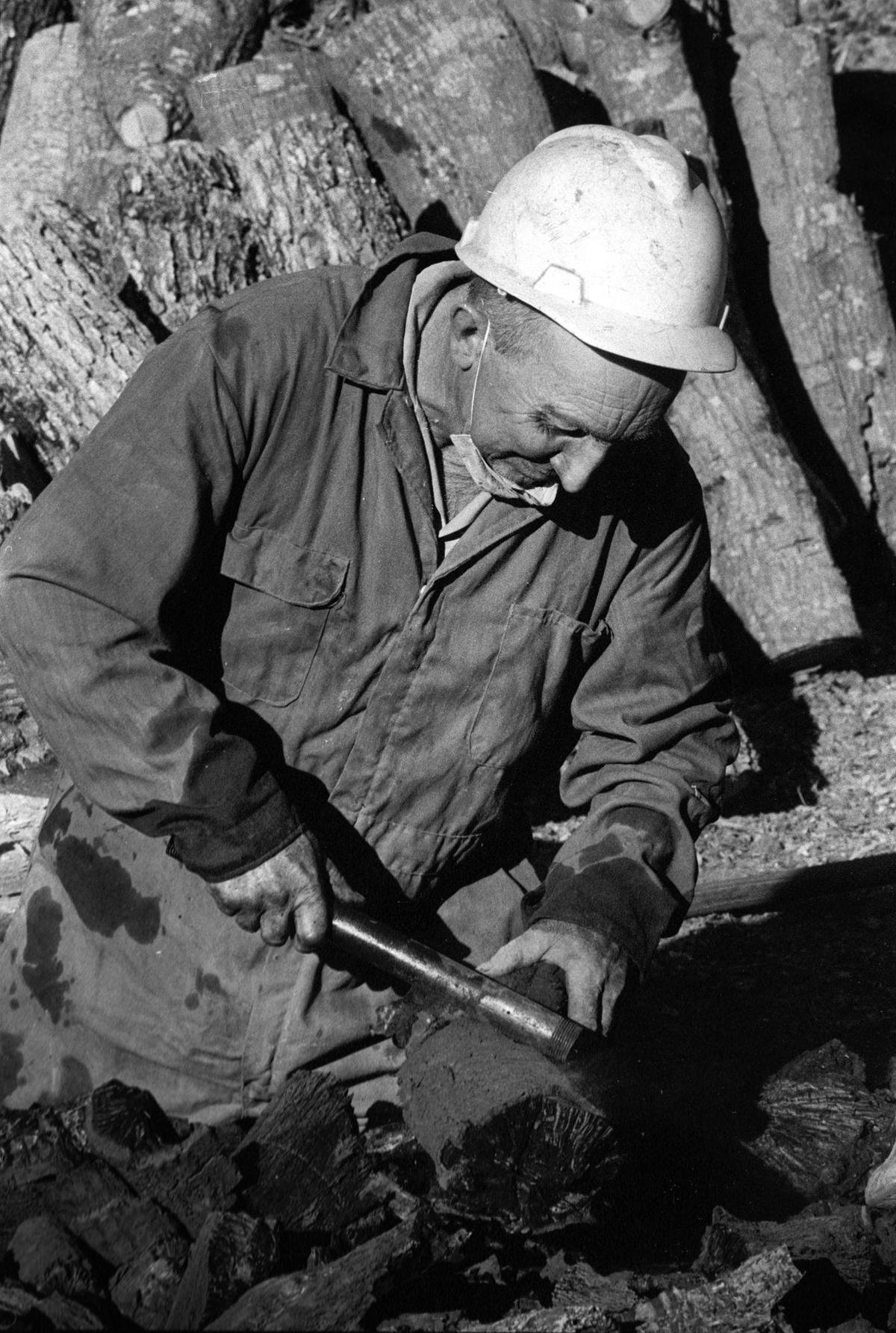 Atillio Busi breaks hot charcoal into pieces with a pipe.