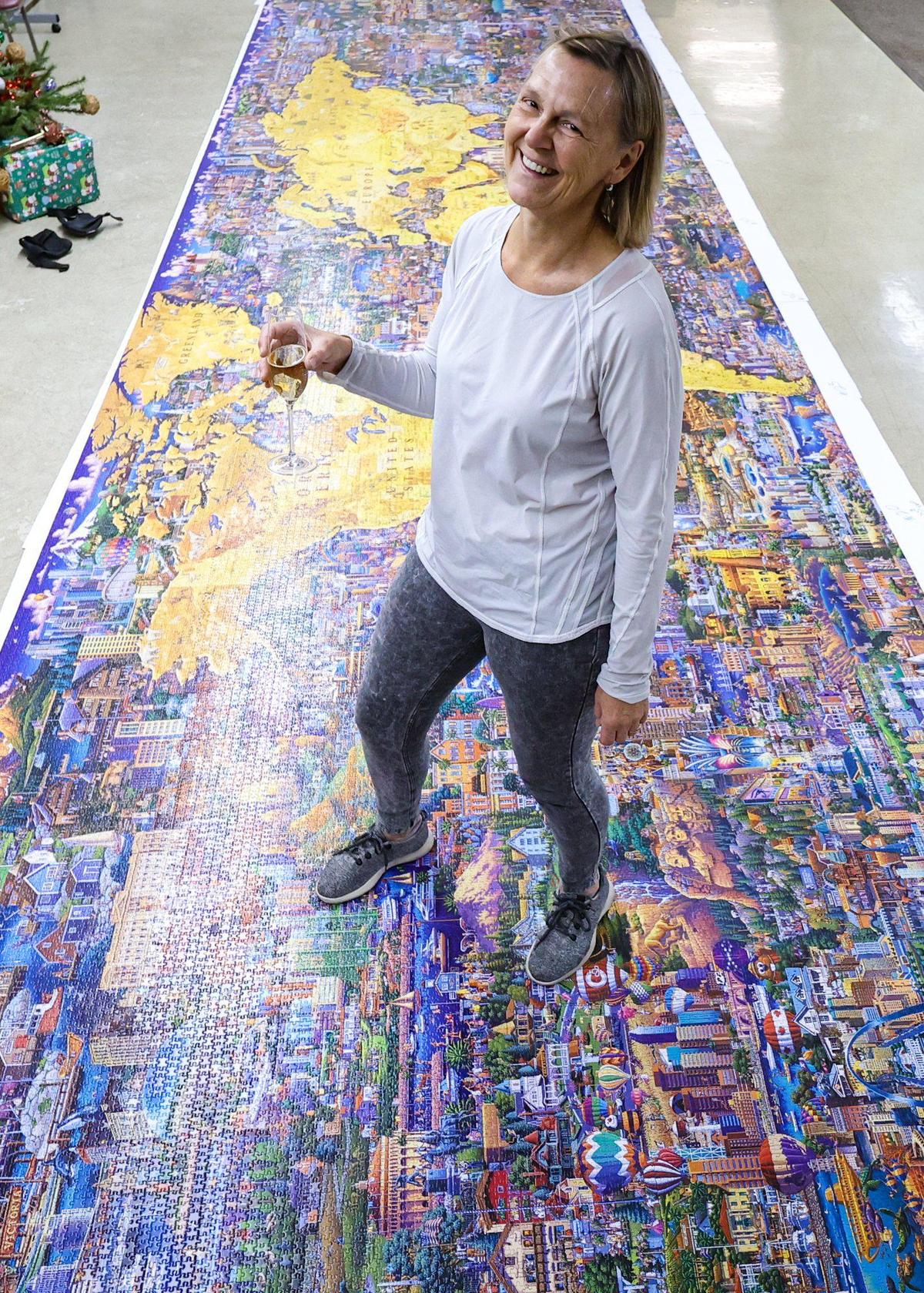 Dr. Minke WinklerPrins enjoys a glass of champagne after she completed a 60,000 piece puzzle larger than a garage door. With help from friends 60 - 1,000 piece sections were assembled Dec. 29, 2022. She started the puzzle at the beginning of November when it was released.