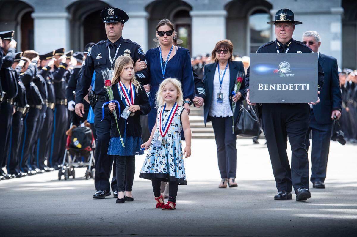 The family of slain San Luis Obispo police Det. Luca Benedetti receives solemn salutes while attending the 44th annual California Peace Officers’ Memorial ceremony on Monday, May 2, 2022, in Sacramento. Benedetti’s widow, Grace, and her daughters Ellie, left, and Giovi were escorted by Atascadero Officer Scott Pipan, a close friend of the family.