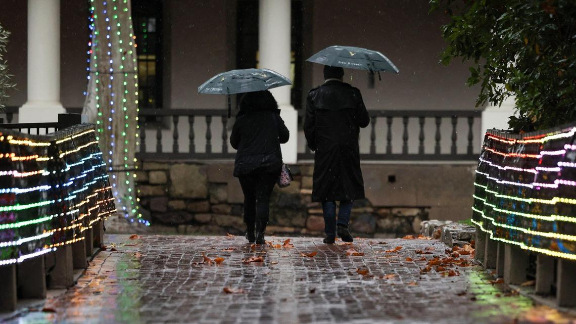Lisa and Bill McIlrath cross the Warden bridge over San Luis Obispo Creek on Dec. 20, 2023, as lights twinkle in Mission Plaza.