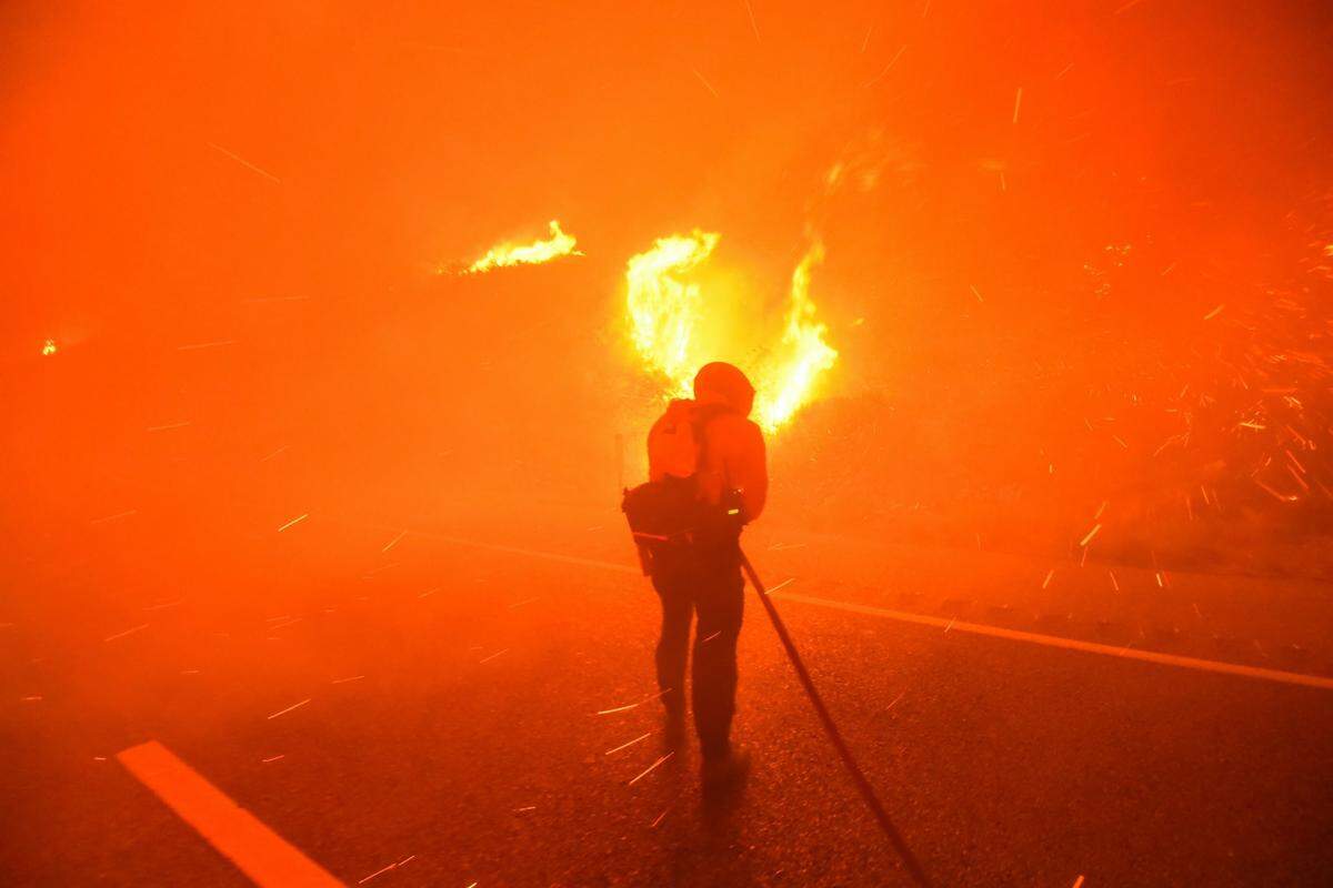 Santa Barbara County Fire Department firefighters knock down flames while standing in the northbound lanes of Highway 101 near Refugio Beach early Tuesday morning. The Alisal Fire had grown to 6,000 acres and was 0% contained as of Tuesday, Oct. 12, 2021. The fire forced the full closure of the highway.