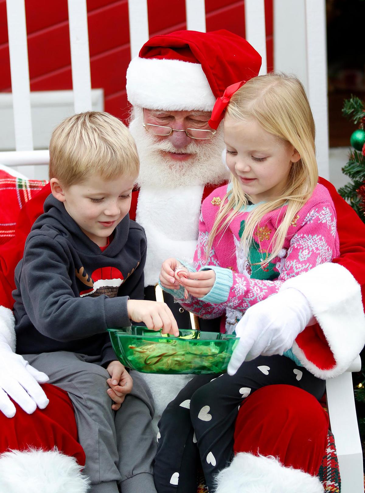 Jameson McBride 4, and Lucy McBride, 6, from San Diego, California, get candy canes from Santa Claus. Joe Schacherer of Oceano, 79, has sat as Santa for 11 years at Downtown SLO’s Santa’s House in Mission Plaza.