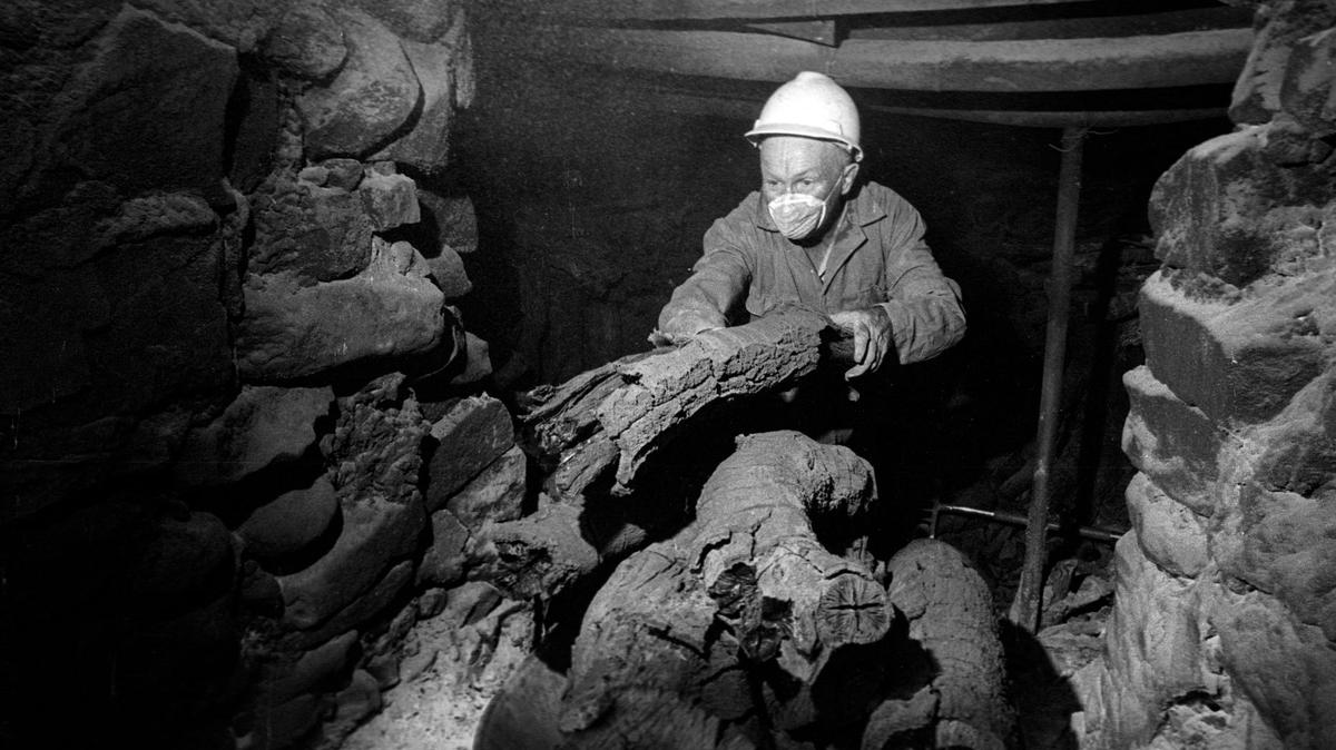 Atillio Busi takes hot charcoal from a kiln to break it into pieces for cooling and packaging.