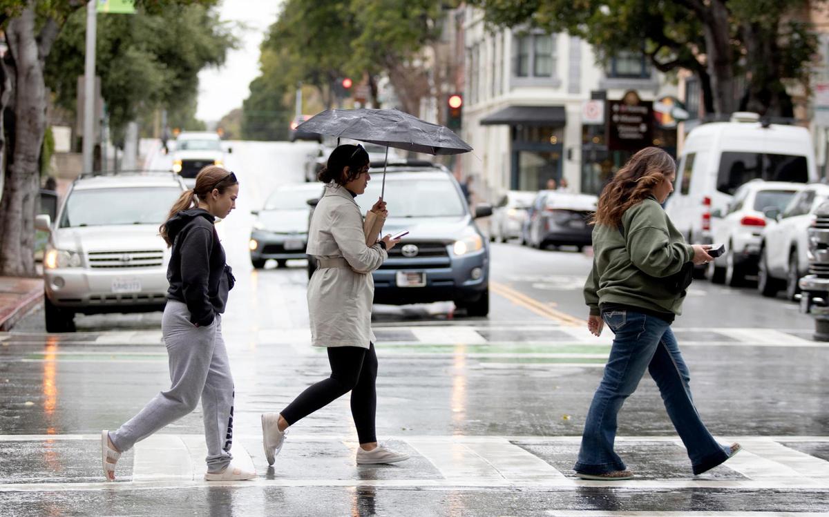 Under a drizzly rain, people cross Higuera Street in downtown San Luis Obispo on Thursday, April 4, 2024.