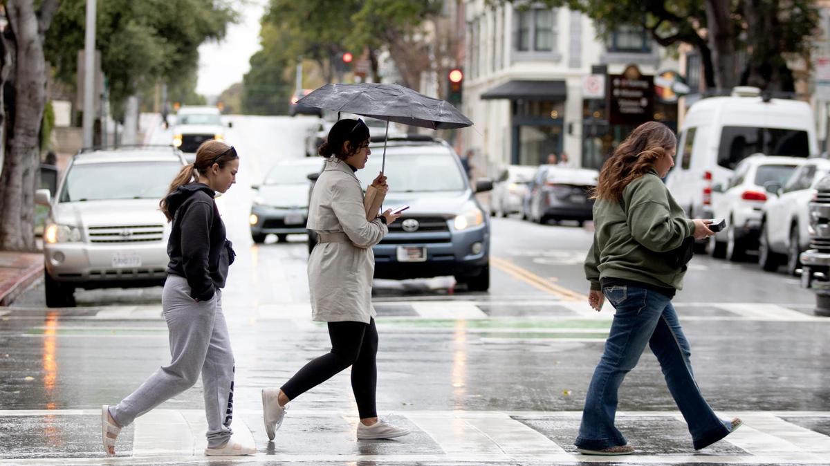 Under a drizzly rain, people cross Higuera Street in downtown San Luis Obispo on Thursday, April 4, 2024.