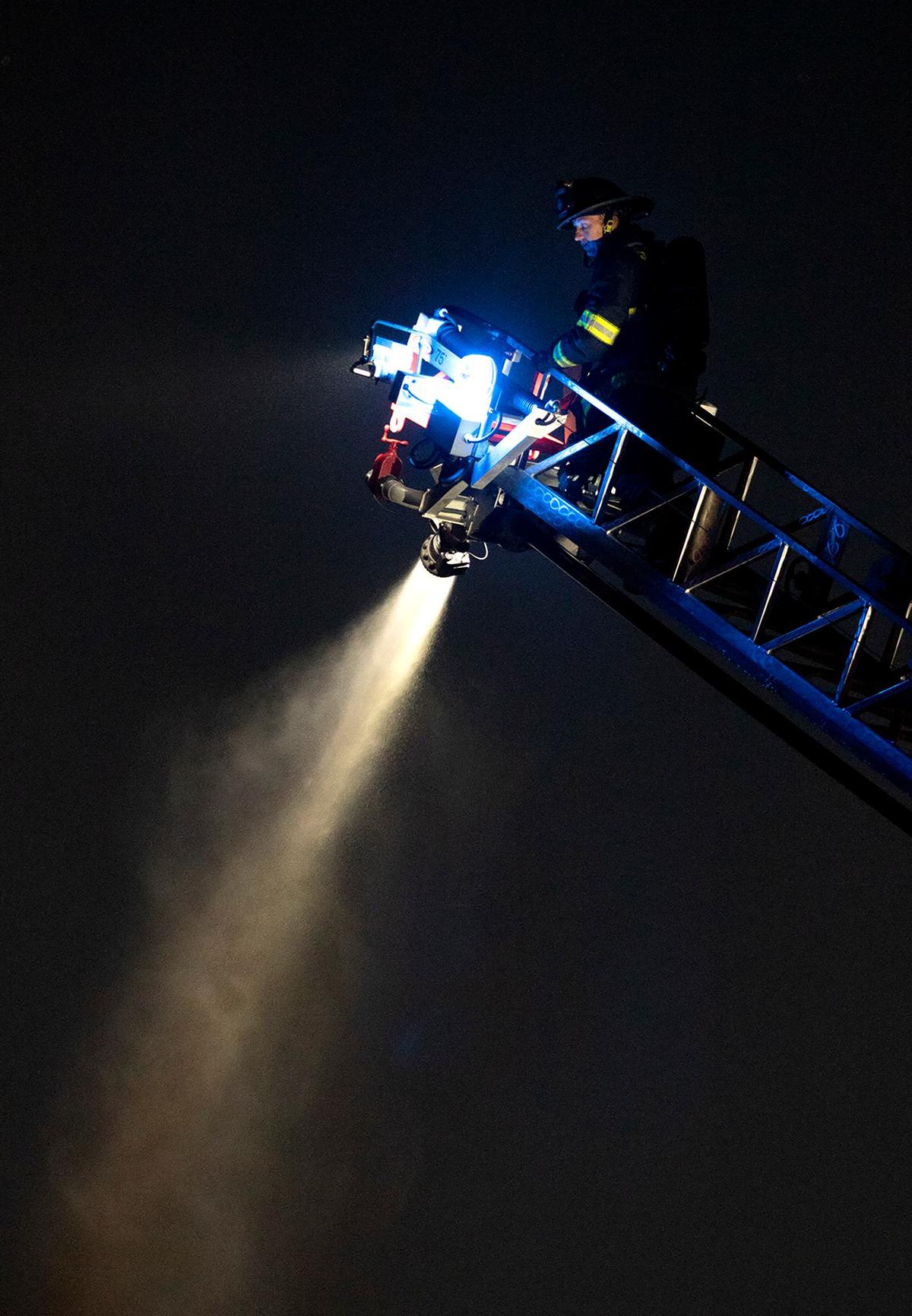 Firefighters responded to a reported house fire in the San Luis Ranch housing development off Froom Ranch Way, Tuesday, June 11, 2024. A firefighter shoots a cannon of water from the ladder truck onto a hot spot on the roof of one of the burned homes.