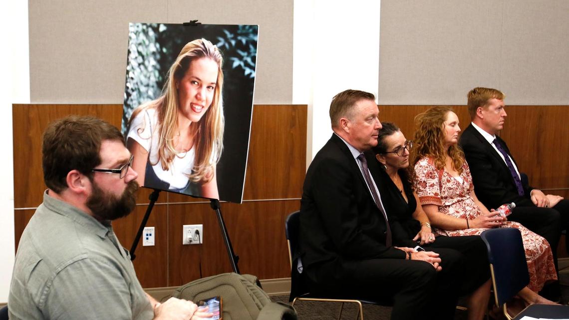 “Your Own Backyard” podcaster Chris Lambert sits in front of a poster of Kristin Smart with family members nearby on Oct. 18, 2022, the day a jury found Paul Flores guilty of murder in Smart’s 1996 disappearance at Cal Poly.