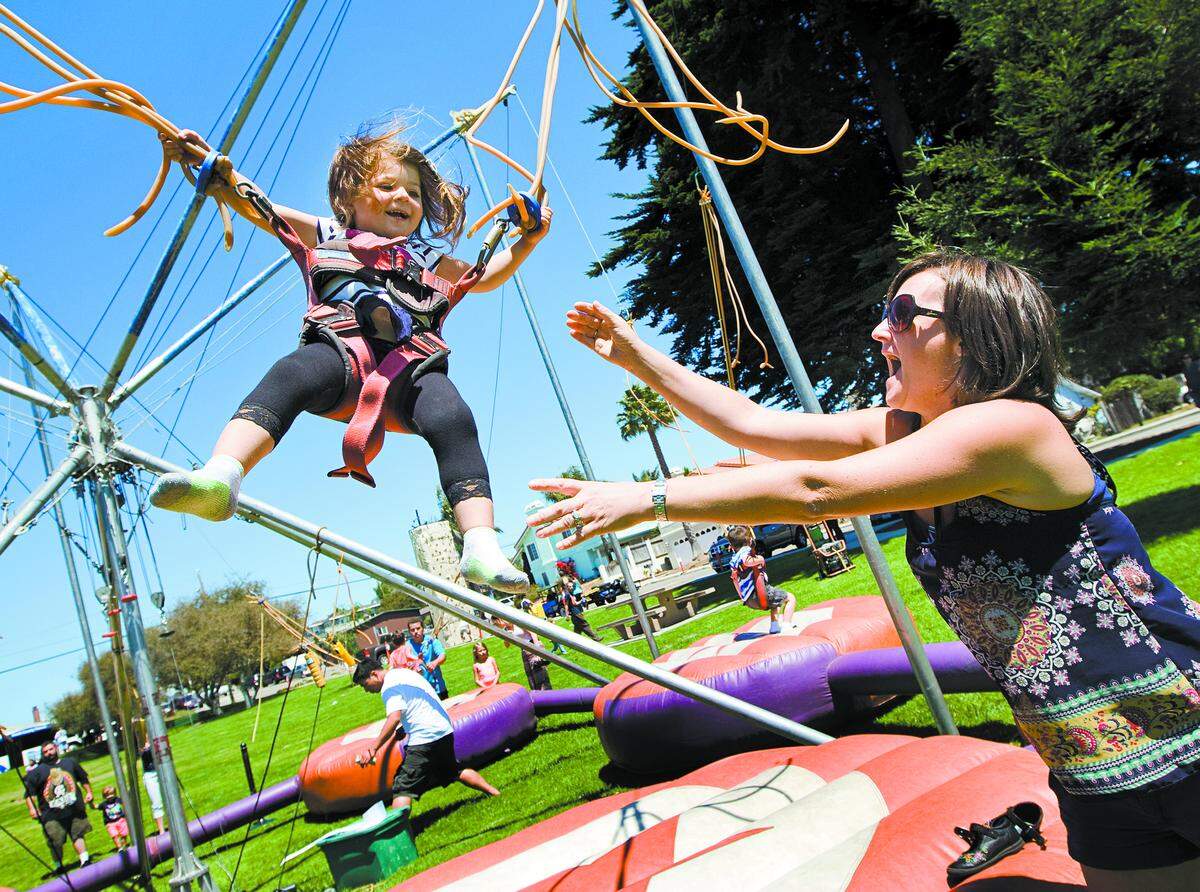 Tanya Freitas of Grover Beach springs her daughter Sierra, 2, into the air on the Bungee Jump ride at the Stone Soup Music Festival, Food and Street Faire in Grover Beach in 2014.  The festival returns to Grover Beach on Aug. 25 and 26.