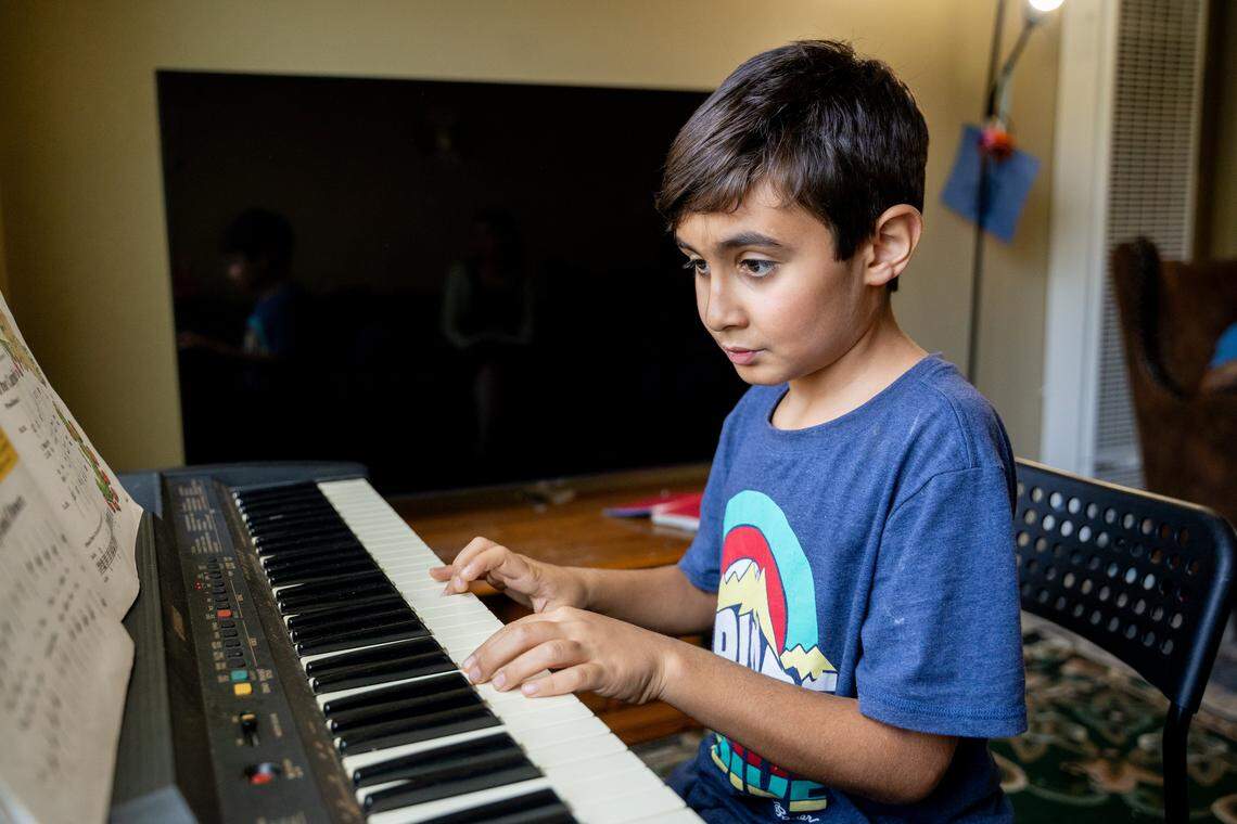 Third grader Parsa Rashvandmeli plays a warmup exercise on the piano in his San Luis Obispo home on Saturday, Oct. 11, 2025. The family recieved music lessons this year at no cost through the Infinite Music program.