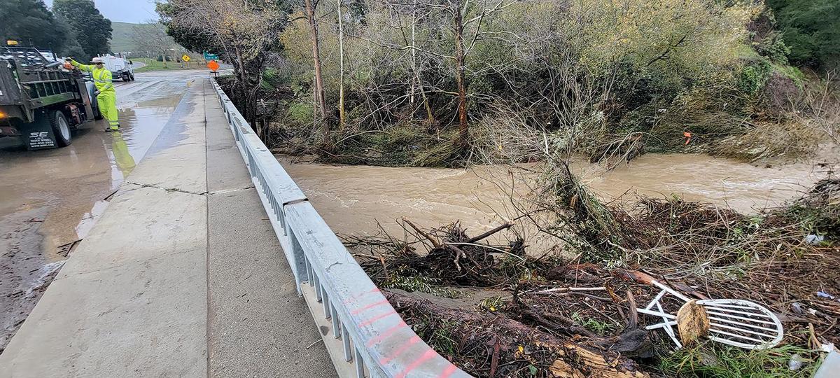 Debris collects in a swollen San Luis Obispo Creek as city workers clean up the intersection of Marsh and Higuera streets on Tuesday, Jan. 10, 2023.