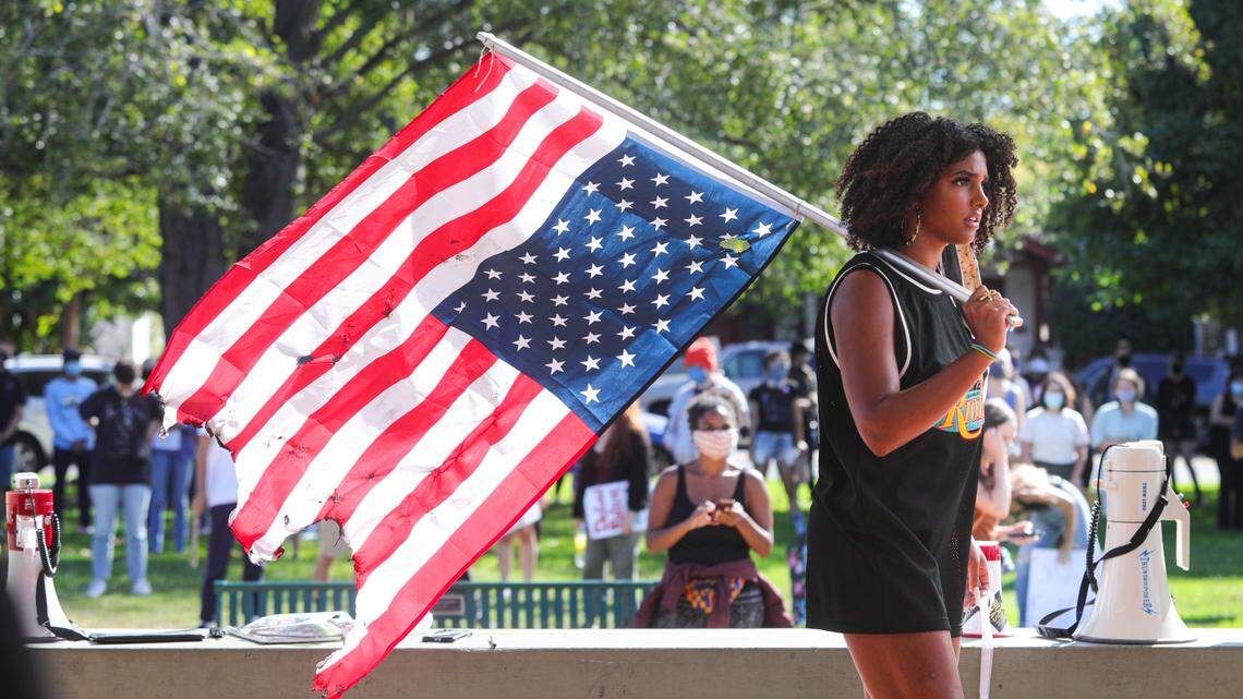Protest organizer Tianna Arata holds a flag during the No Justice No Peace protest, which began at Mitchell Park in San Luis Obispo on July 21, 2020.
