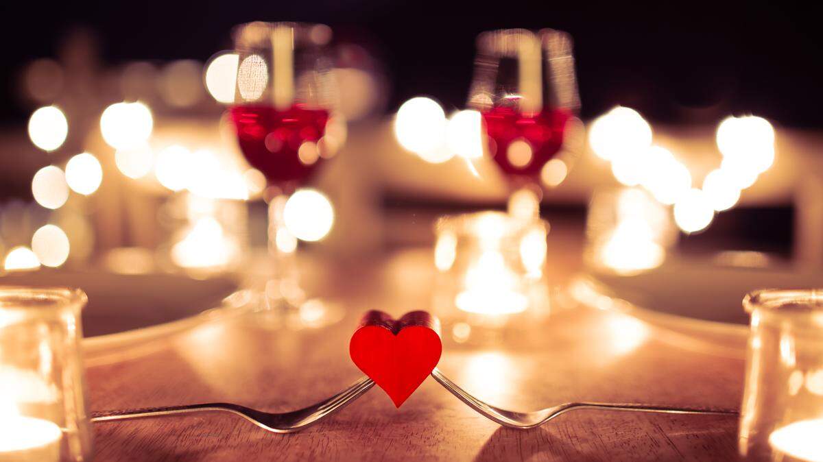Closeup of heart in a valentines candlelight dinner date setting.