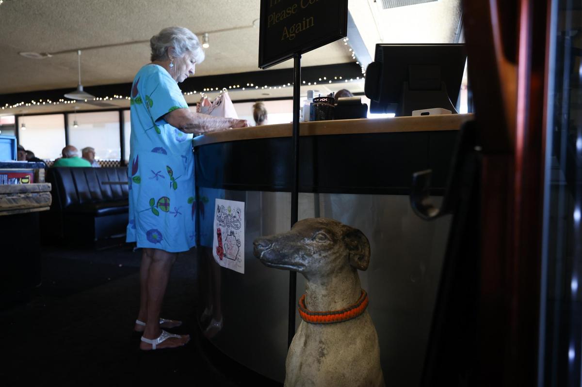 Customer Barbara Jones of Paso Robles pays for her meal at A-Town Diner on Thursday, near an Atascadero greyhound mascot at the counter. The last day for the restaurant will be Sunday, Sept. 4.