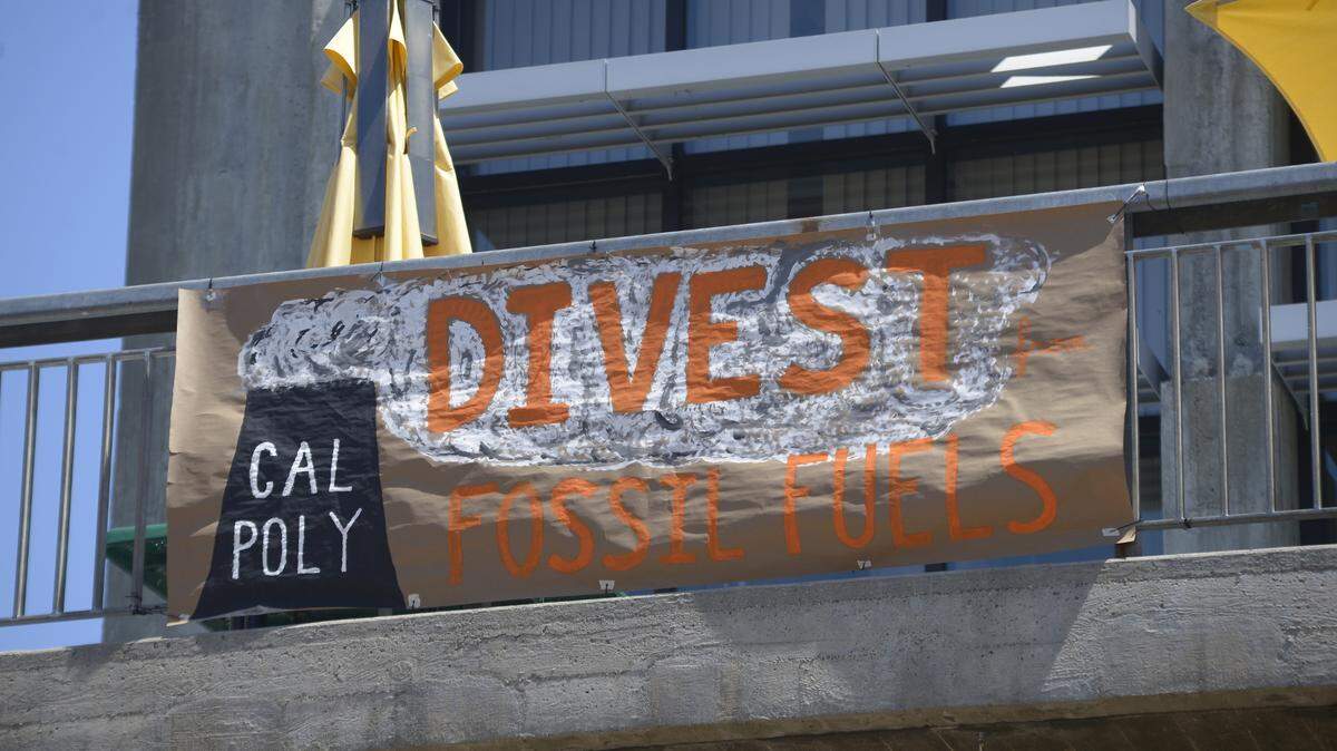 A banner hangs at the Cal Poly campus in San Luis Obispo, calling for the university to divest all investment portfolios from fossil fuel companies.