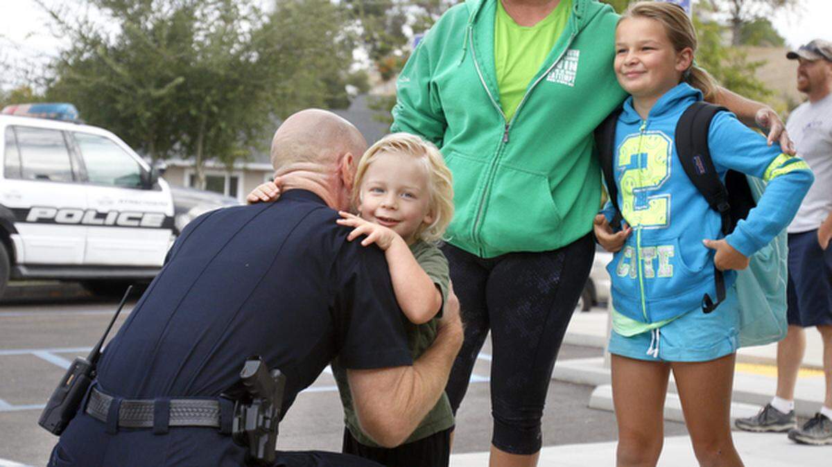 Parker Watty, 3, gets a hug from Atascadero police Chief Jarel Haley. Parker was excited that the "woo woo cars" were parked in front of his sister's school. Sister Aly, 8, and mom Jody are in the background. 