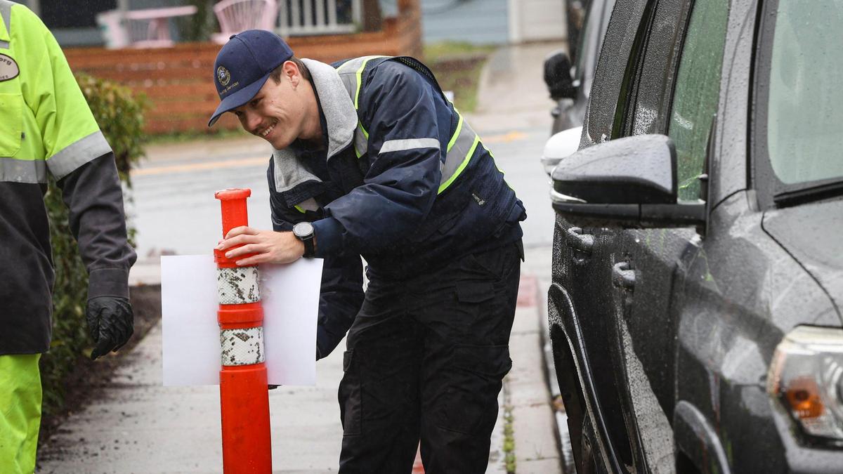 Parker Venneau with San Luis Obispo City Parking Services staples up temporary no parking notices along Hathway Avenue on March 14, 2025., the day before St. Fratty’s Day.