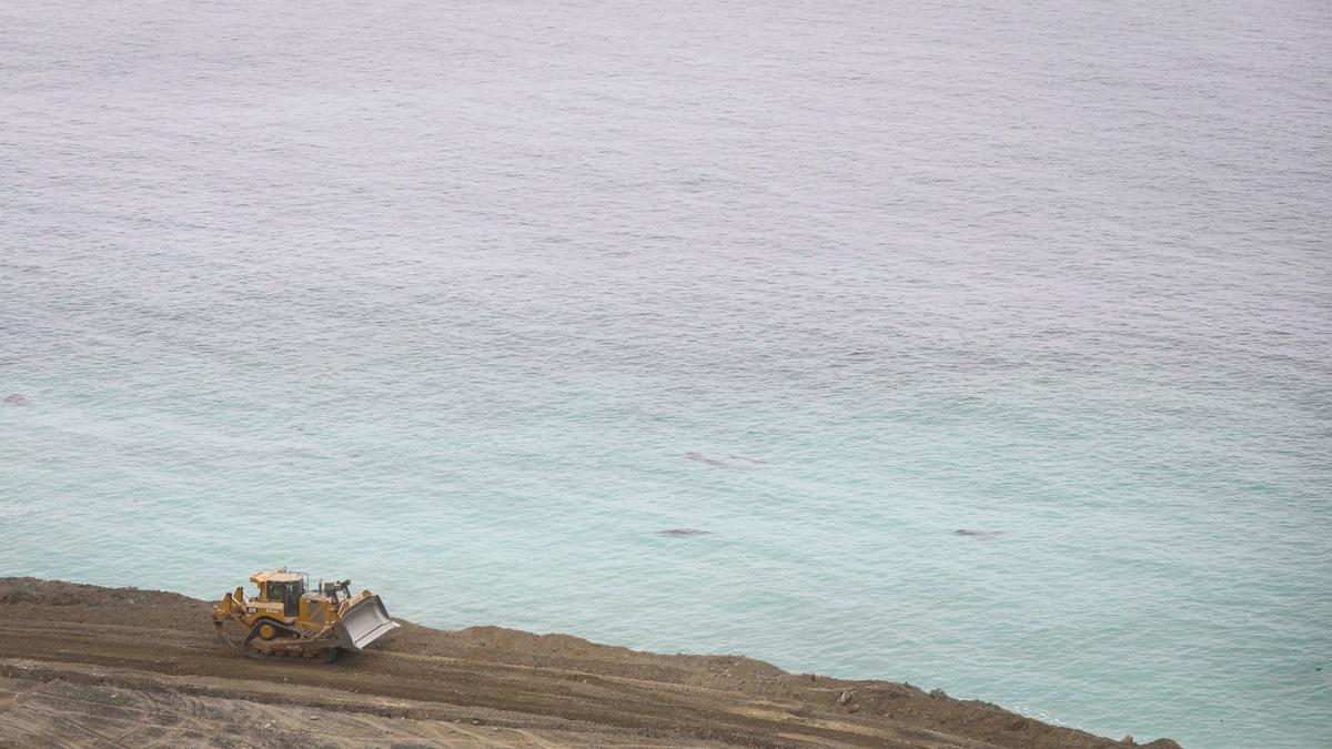 Bulldozer pushes and compacts dirt for a fill area below the highway grade at the edge of the Pacific Ocean. Crews from Papich Construction Co. work on Paul’s Slide on Highway 1 north of Gorda on May 17, 2024. Repairs are expected to be completed this summer.
