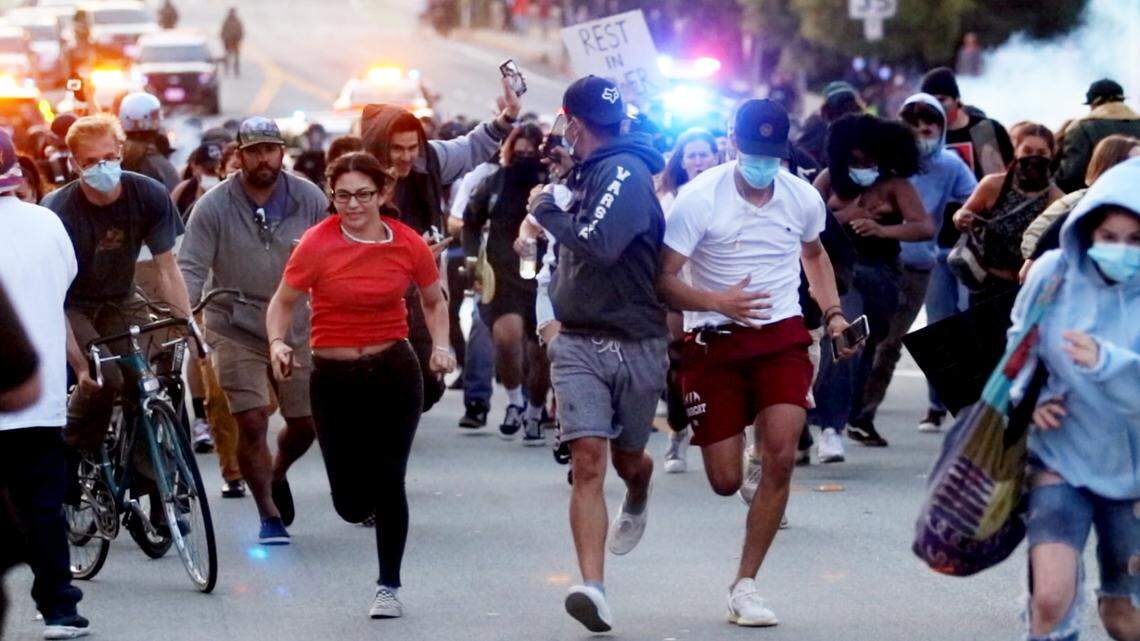 Black Lives Matter protesters retreat as tear gas is fired near the police station in San Luis Obispo on June 1, 2020.