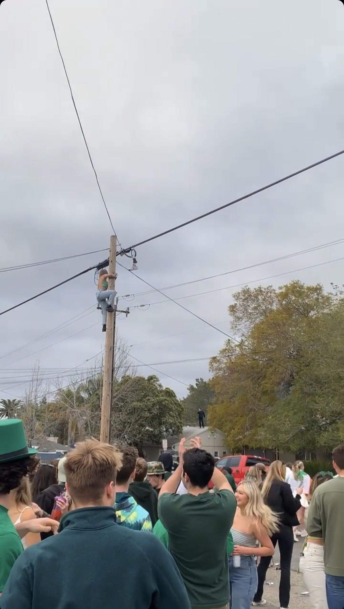 A woman climbed a utility pole as a crowd watched as part of a St. Fratty's Day celebration Saturday morning, March 13, 2021 in San Luis Obispo, Calif., according to a video posted on Cal Poly Barstool’s Instagram story. 
