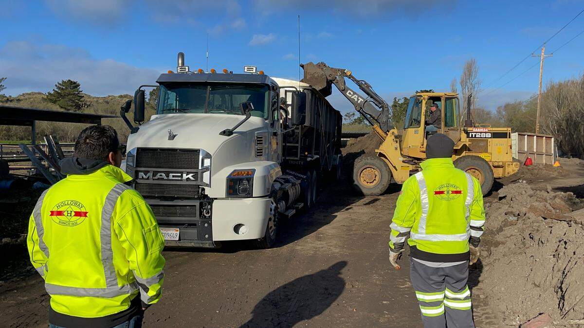 Volunteers standing nearby machines cleaning up debris on the Cardoza ranch, Feb. 11, 2023.