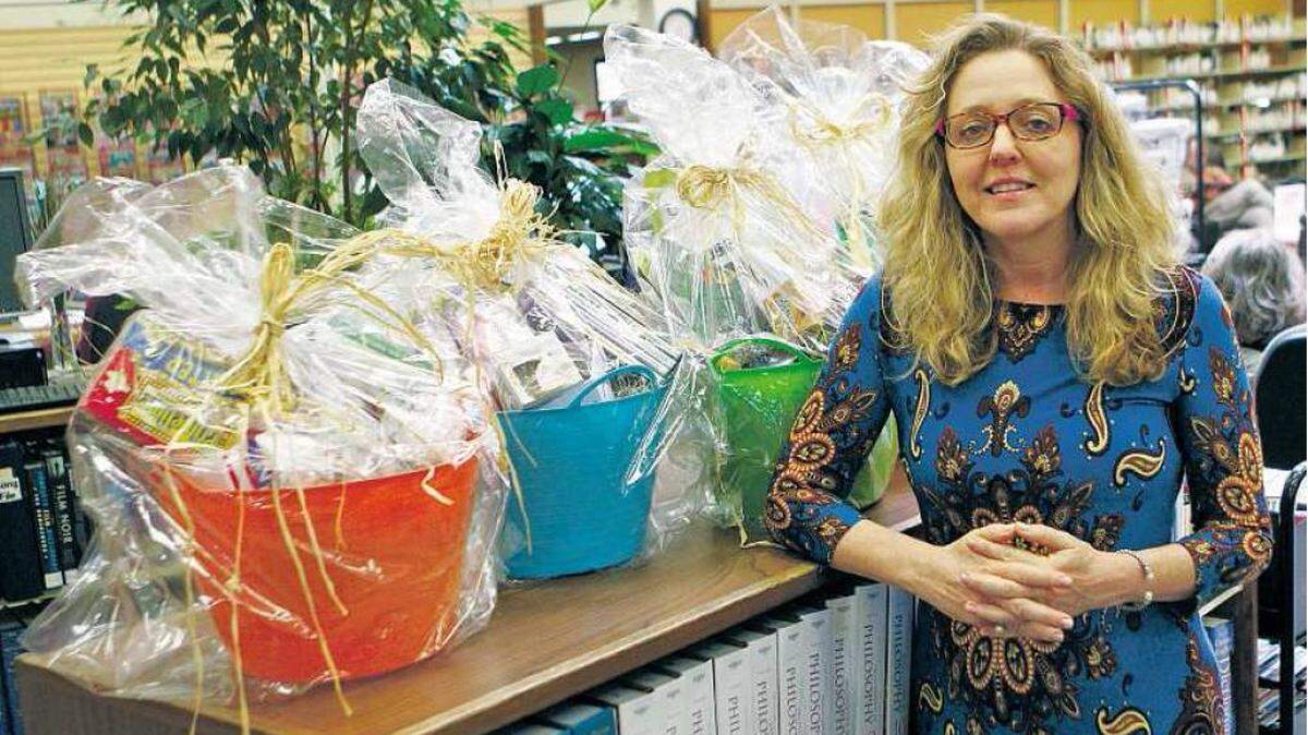Rosalyn Pierini, regional librarian with the SLO County Library in Arroyo Grande, poses with gift baskets that are part of a drawing for adult summer reading participants.
