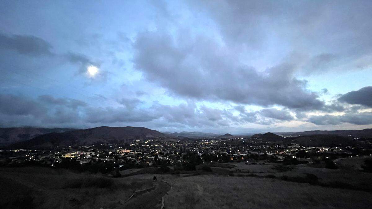 The moon rises over the city lights of San Luis Obispo at dusk in a view from the peak of Cerro San Luis.