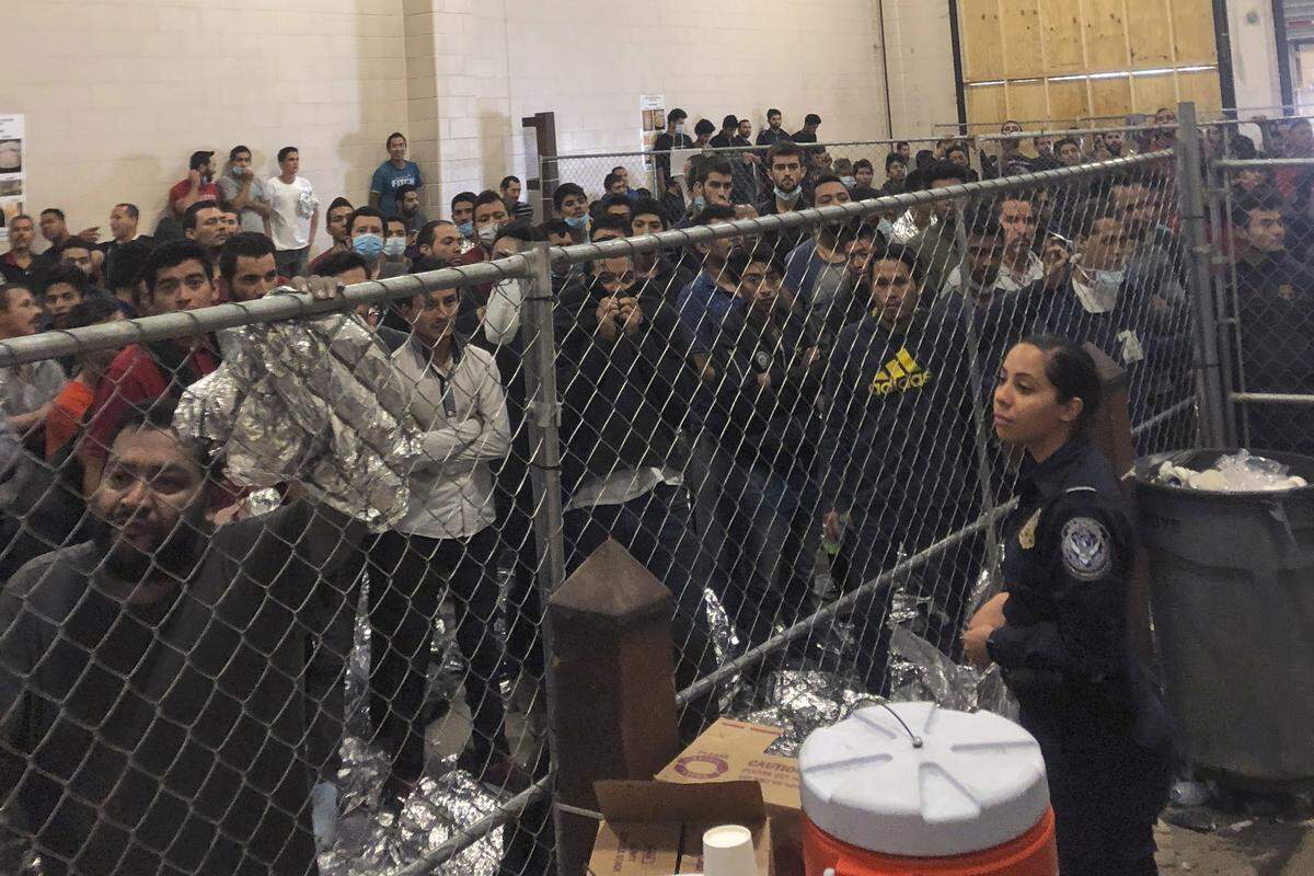 In this July 12, 2019 file photo, men stand in a U.S. Immigration and Border Enforcement detention center in McAllen, Texas, during a visit by Vice President Mike Pence.