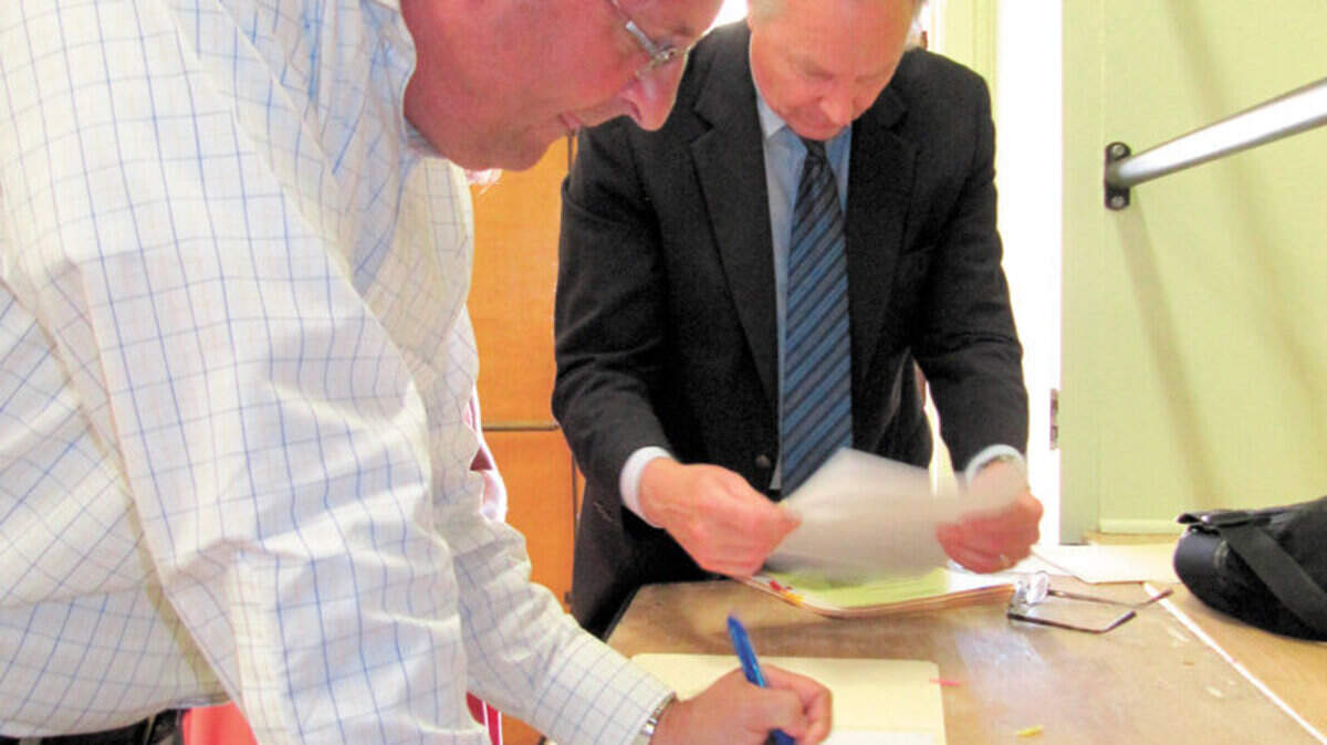 Jerry Gruber, left, general manager of the Cambria CSD, signs loan papers Monday, Aug. 4, at the Veterans Memorial Building with Charles ‘Chick’ Adams, the district’s bond counsel from the Jones Hall legal firm in San Francisco.