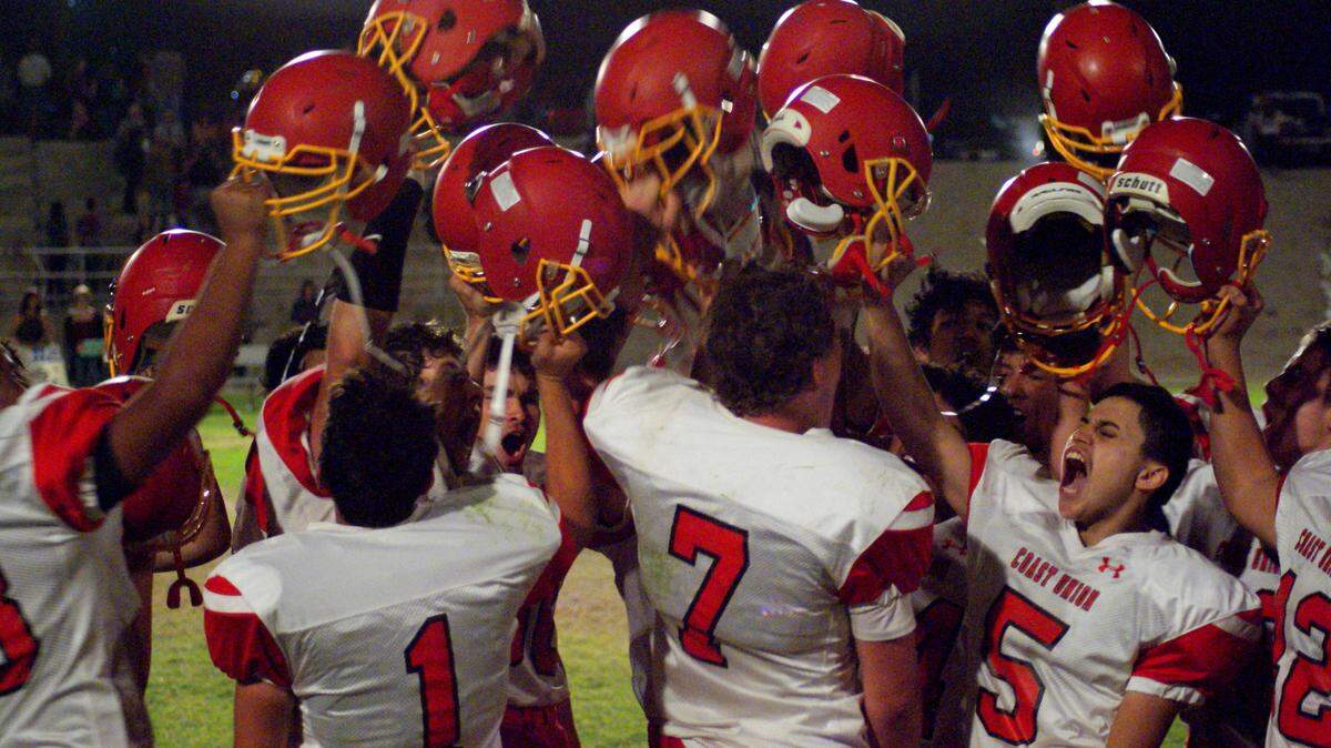 Coast Union High School players raise helmets high in the air after a victory over league opponent Maricopa in 2020.