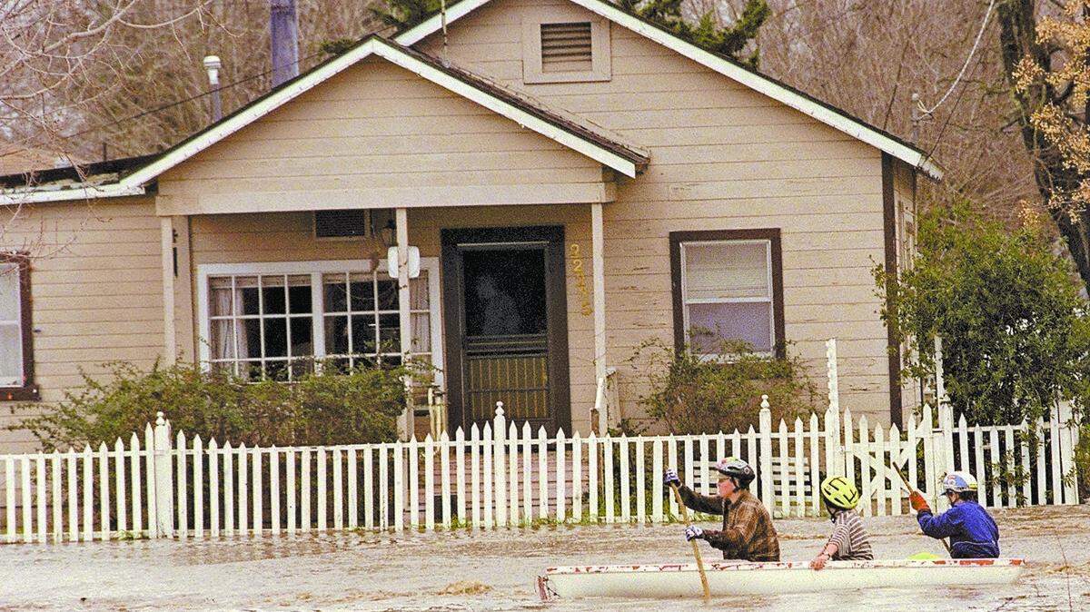 A trio of canoeists brave the waters of H Street in Santa Margarita after a storm in February 1998 caused creeks to overflow.