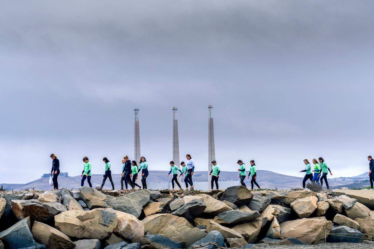 Junior Lifeguards participants walk along the sand spit in Morro Bay with the stacks of the former Duke Energy power plant towering behind them. San Luis Obispo photographer Mark Nakamura captured the scene on July 1, 2020 while hiking from the edge of Montana de Oro State Park in Los Osos to the opening of Morro Bay.