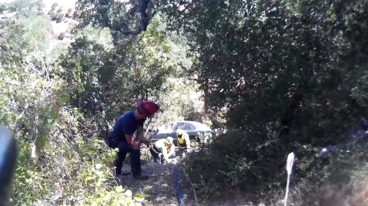 Emergency responders worked Sunday to free a person trapped in a car that plunged 50 feet down an embankment in Atascadero.