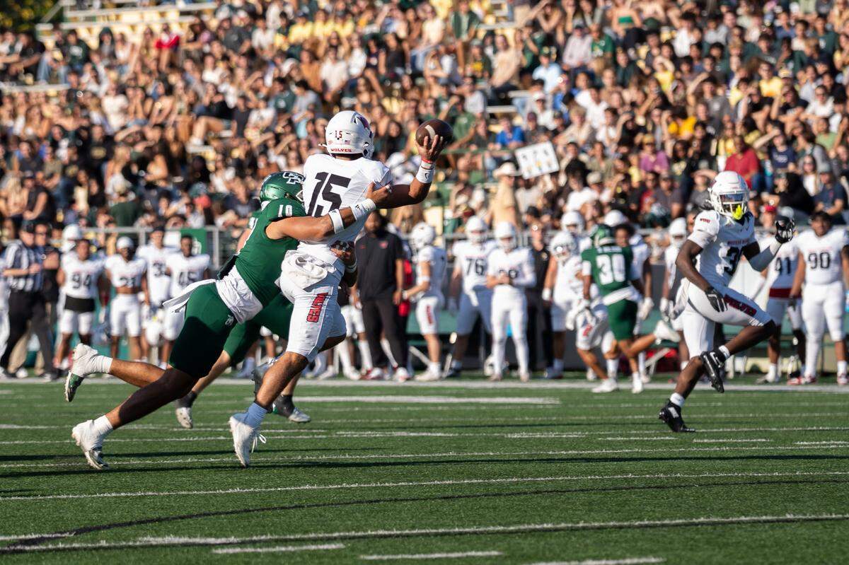 Western Oregon quarterback Jordan McCarty throws away the football to avoid being sacked by Cal Poly defensive lineman Victory Johnson in the first quarter on Saturday, Sept. 13, 2025. The Mustangs defeated the Wolves in a 56-7 rout at home.