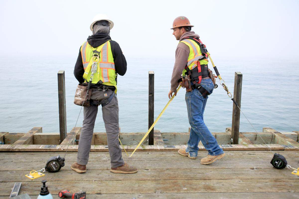 Ben Scilepi, left, and Hank Linder of Hartzell Construction, work to repair a portion of the railing on the damaged Cayucos Pier, on Oct. 31, 2025.
