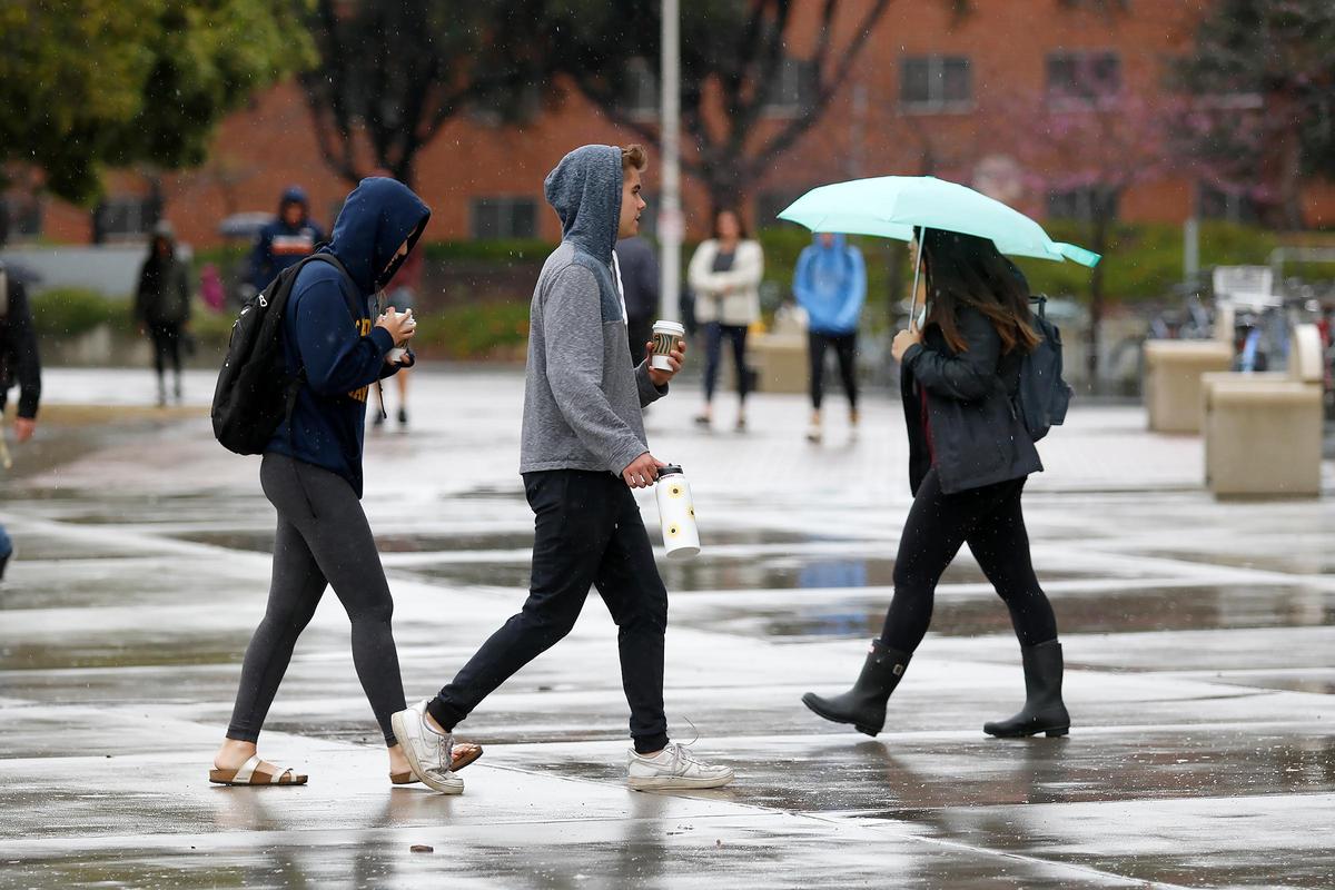 Cal Poly students are traveling home for break despite the coronavirus spreading. Students walk in a light rain next to the University Union.
