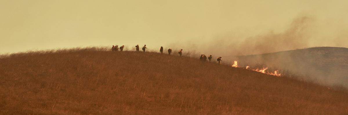 A Santa Barbara County Fire Department hand crew works on a hilltop to battle the Alisal Fire.